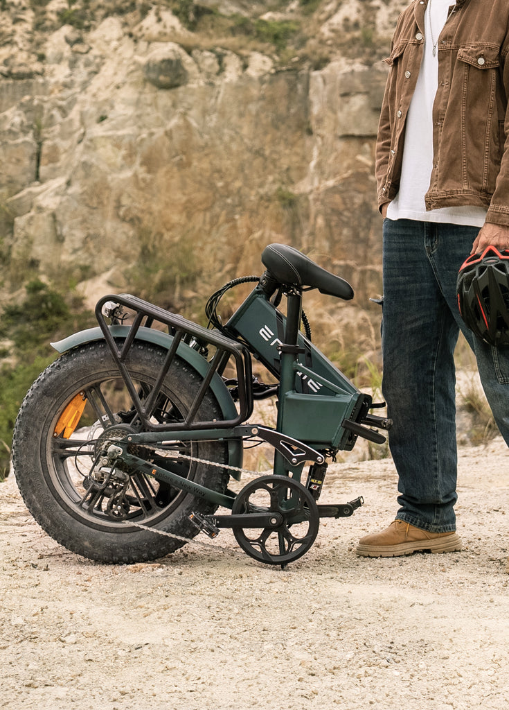 a man stands next to a folded mountain green engwe engine pro 2.0 e-bike